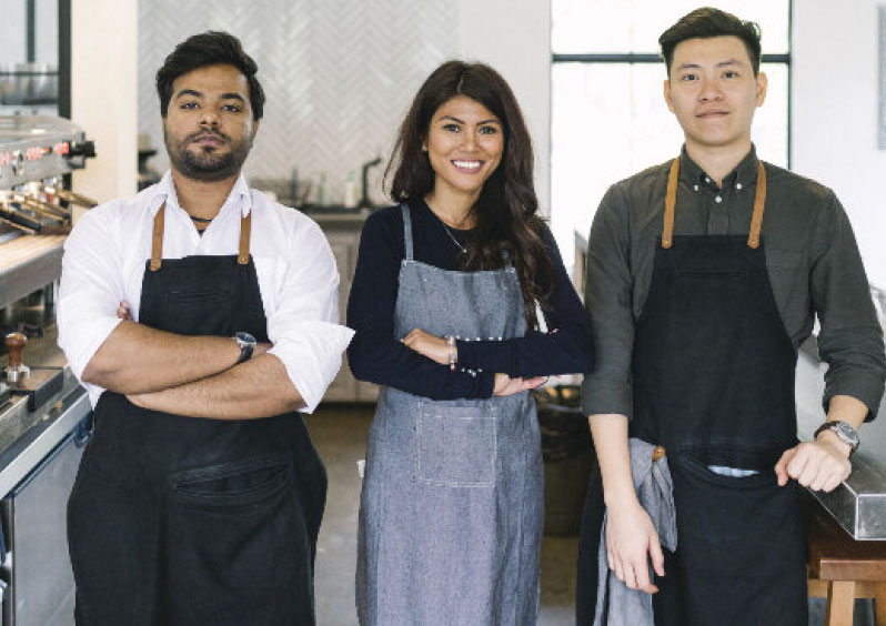 team of three people in aprons left two crossing arms